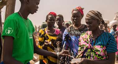 Ein Mann im grünen T-Shirt verteilt Essen an Menschen im Südsudan