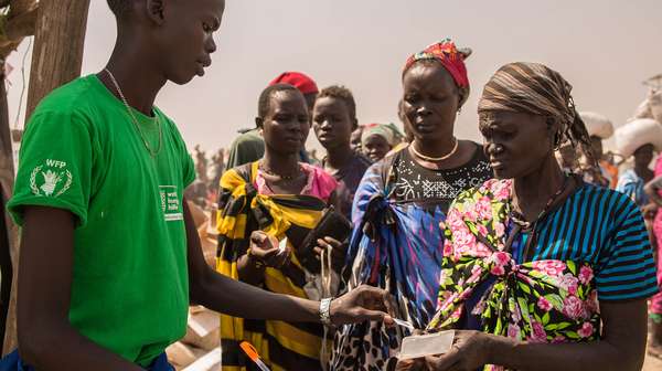 Ein Mann im grünen T-Shirt verteilt Essen an Menschen im Südsudan
