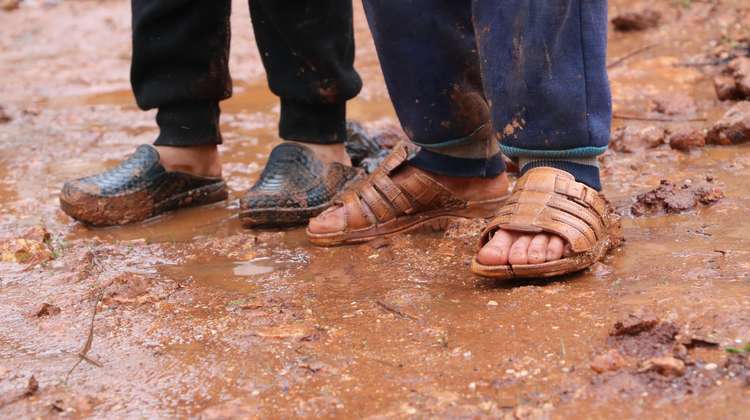 Kinder mit Sandalen im Schlamm, Syrien 2019.