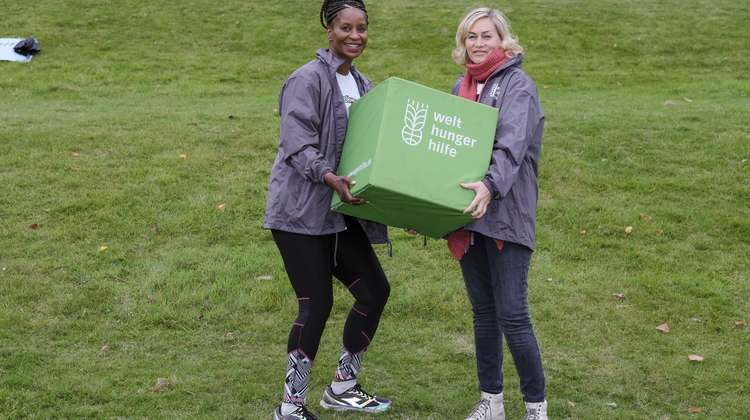 Zwei Frauen halten einen grünen Würfel mit Welthungerhilfe-Logo.