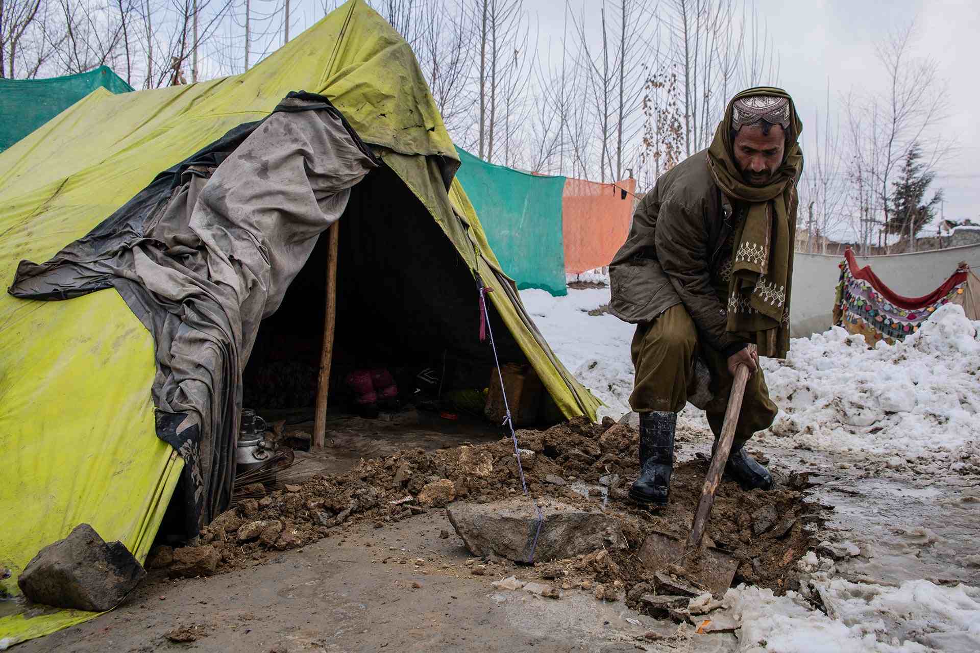 Ein Mann befreit seinen Zelteingang von Schnee und Matsch. Die dünnen Zeltplanen schützen nicht vor der eisigen Kälte des aghanischen Winters.