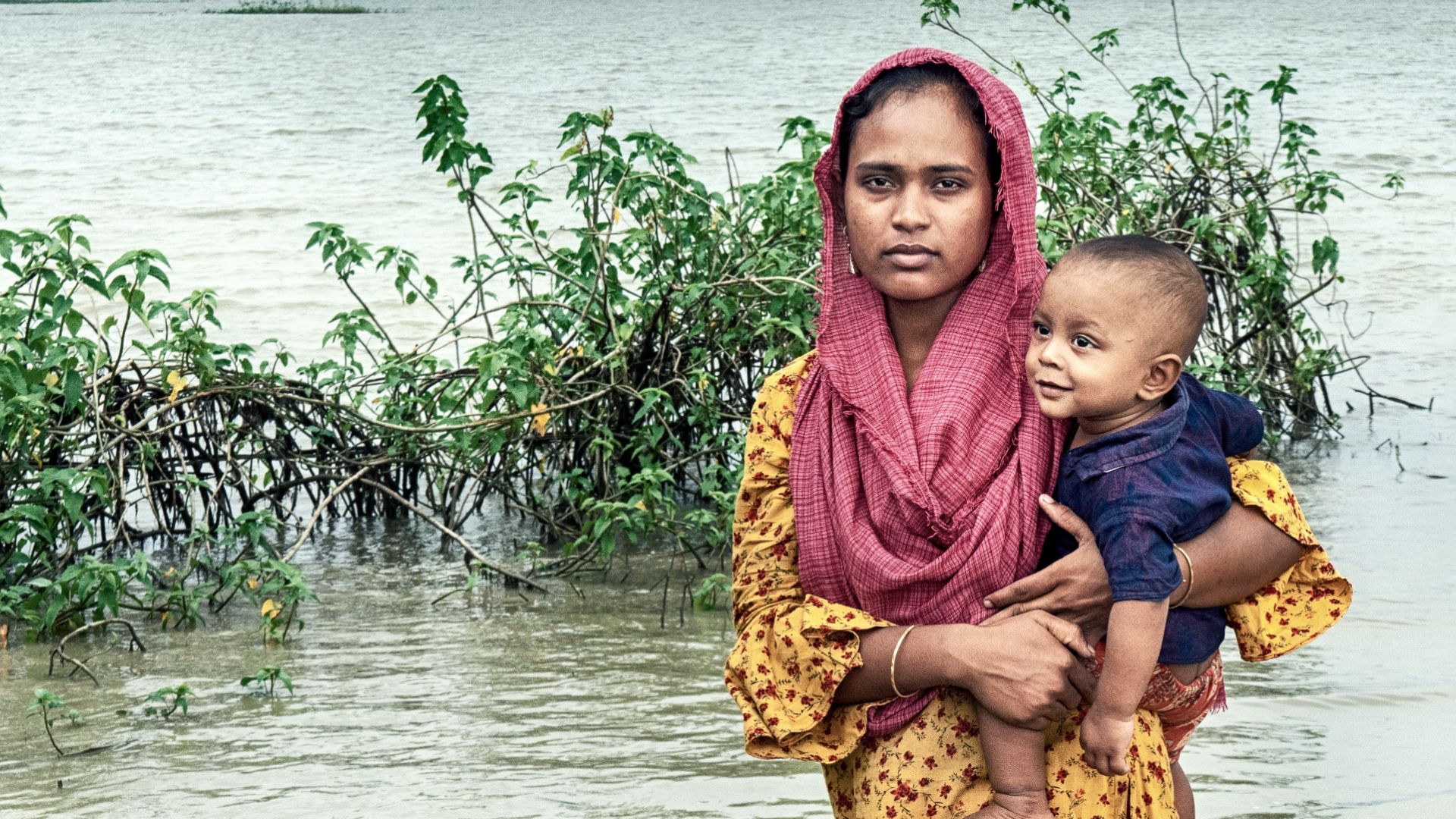 Eine Mutter steht mit ihrem Kind in den Fluten.